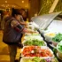 People serving themselves salad from a bright buffet line with bowls of greens and toppings at a restaurant or cafeteria.