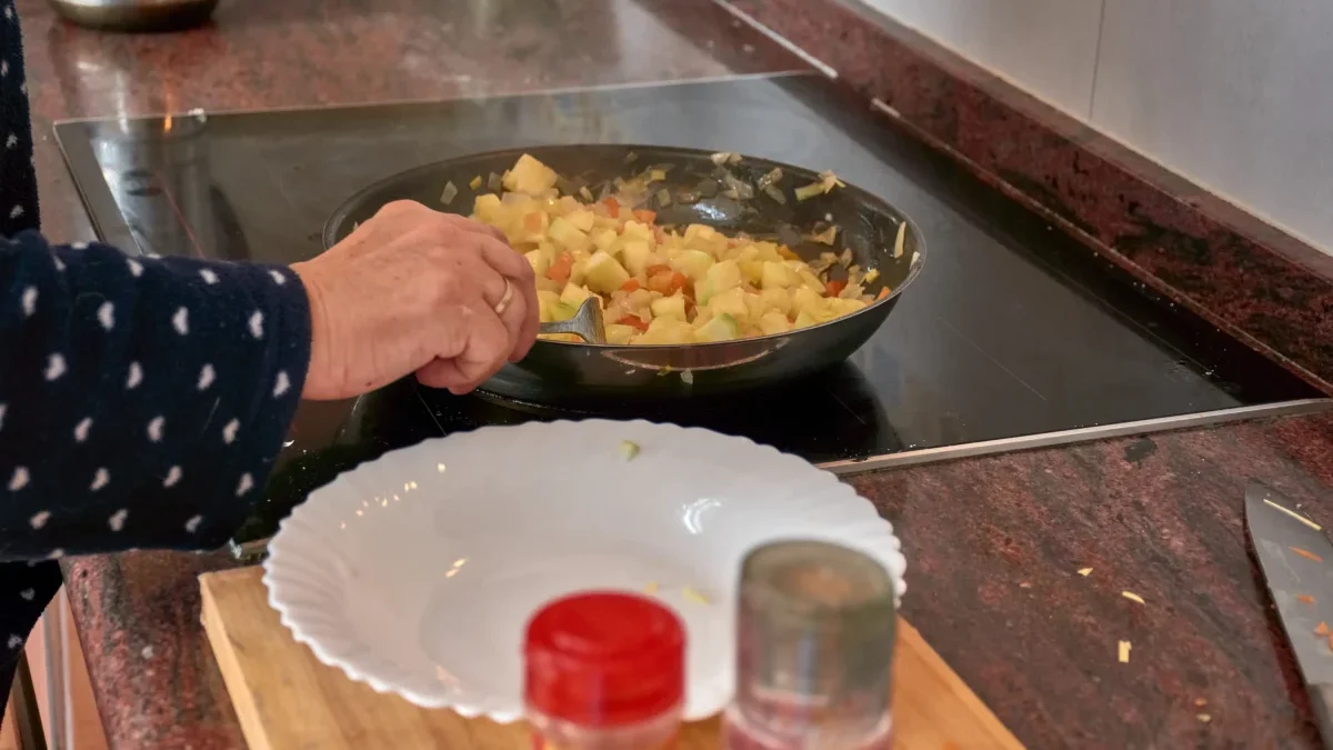 Ruce míchající jídlo na pánvi