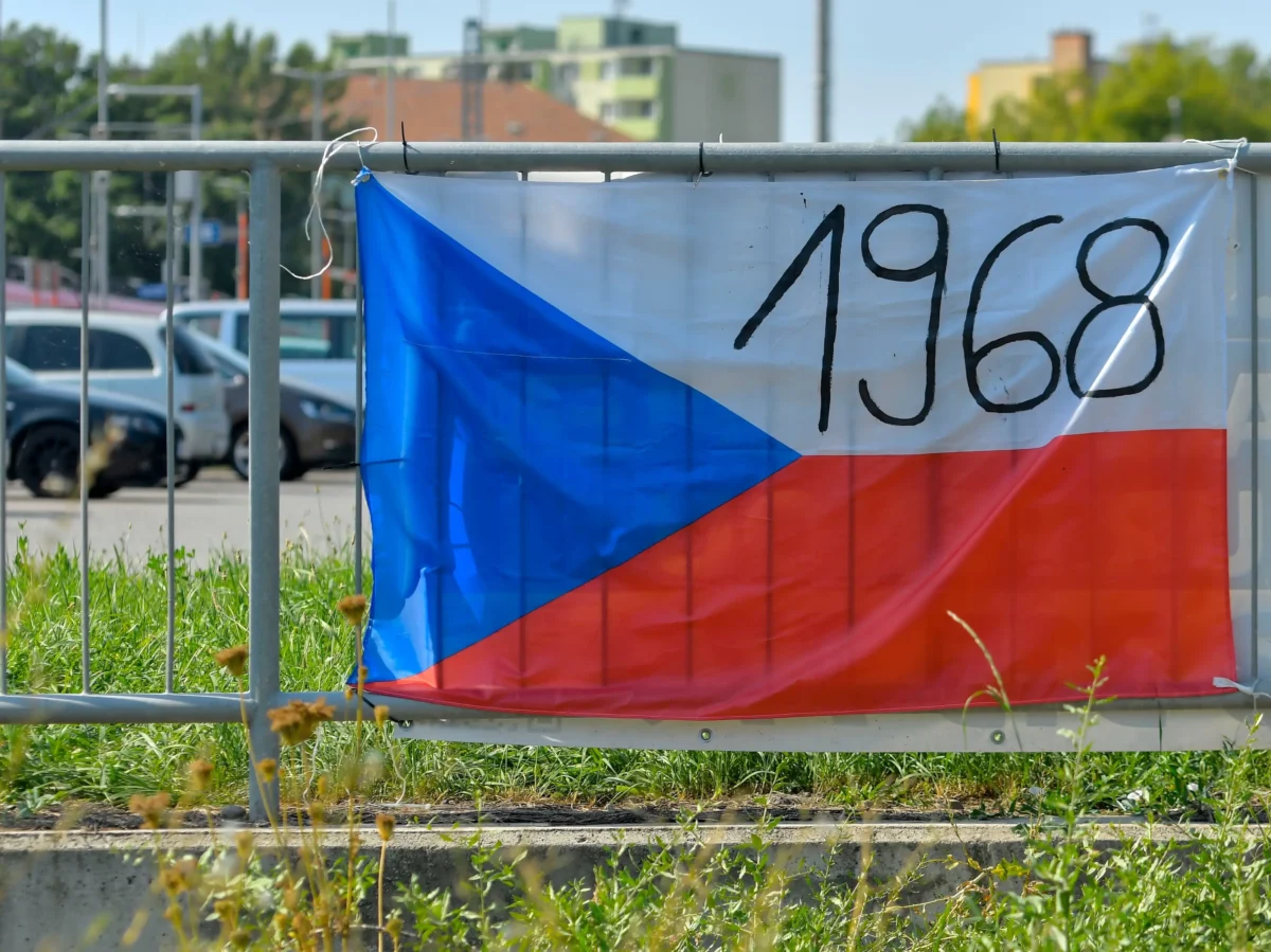 Na plotě visí česká vlajka s nápisem 1968.