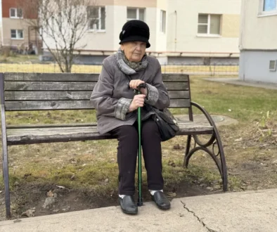 seniorka v klobouku s holí sedící na lavičce