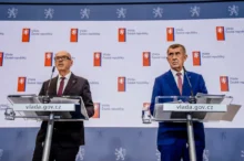 Dva muži v oblecích u pultíků s mikrofony