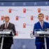 Dva muži v oblecích u pultíků s mikrofony