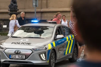 Lidé postávají u policejního auta.