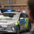 Lidé postávají u policejního auta.