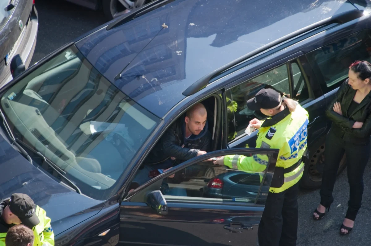 shutterstock_2540964159-2 | TVGURU.cz Policista stojí u auta, ve kterém sedí muž.