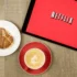 Na tabletu je puštěný Netflix a vedle leží svačina s kávou.