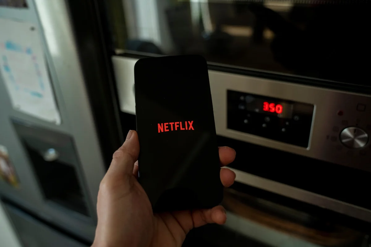 Člověk v ruce drží telefon s Netflixem.