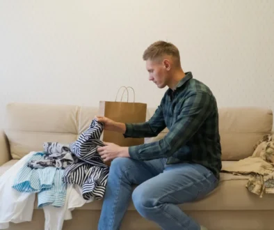 Muž na gauči rozbalující nové oblečení.
