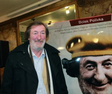 Bolek Polívka stojí před svým plakátem.