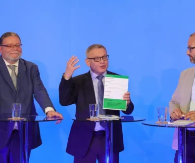 Tři muži v oblecích u moderovacích pultíků