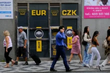 Lidé chodí po ulici kolem bankomatu