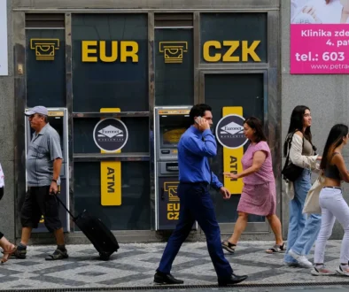 Lidé chodí po ulici kolem bankomatu