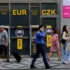 Lidé chodí po ulici kolem bankomatu