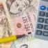 Close-up of euro banknotes with a calculator and yellow pencils, suggesting financial calculations.