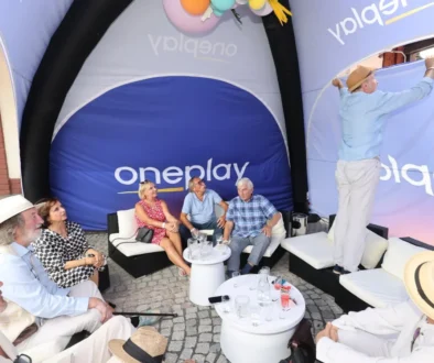 stan s nápisem Oneplay a lidé pod ním
