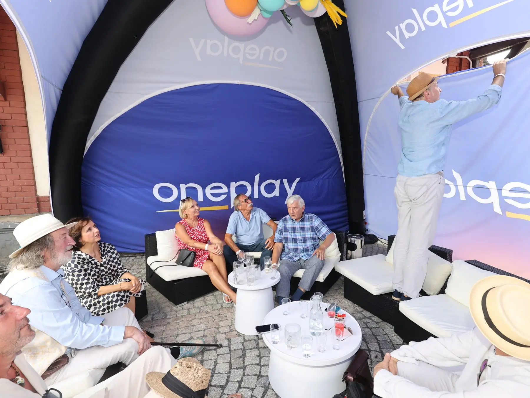 stan s nápisem Oneplay a lidé pod ním