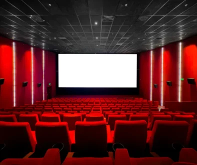 Red-walled cinema interior with a large white screen at the front and red seating throughout the auditorium.