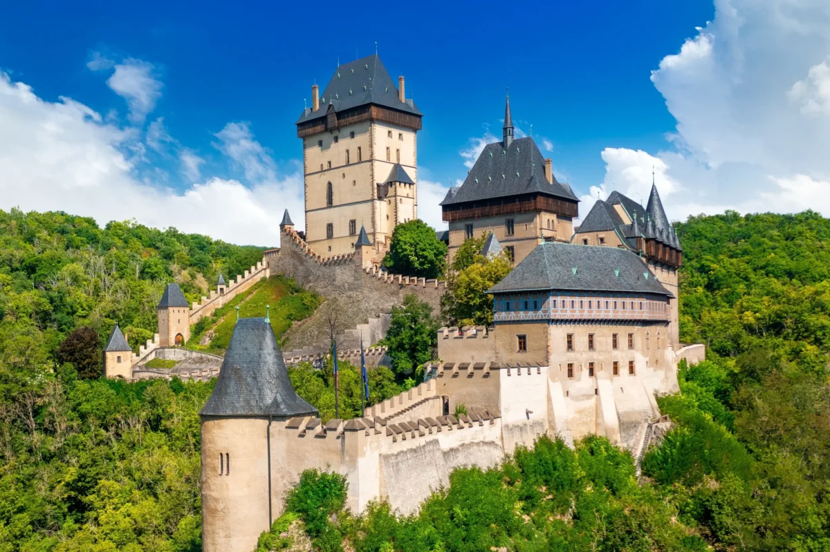 Pokračovat bude i zábavný pořad s informacemi o České republice. Zdroj: Shutterstock | TVGURU.cz Hrad Karlštejn s lesy okolo.