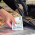 Ruka drží českou stokorunu, vedle je platební terminál