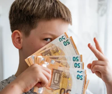 Chlapec drží vějíř eurových bankovek před obličejem