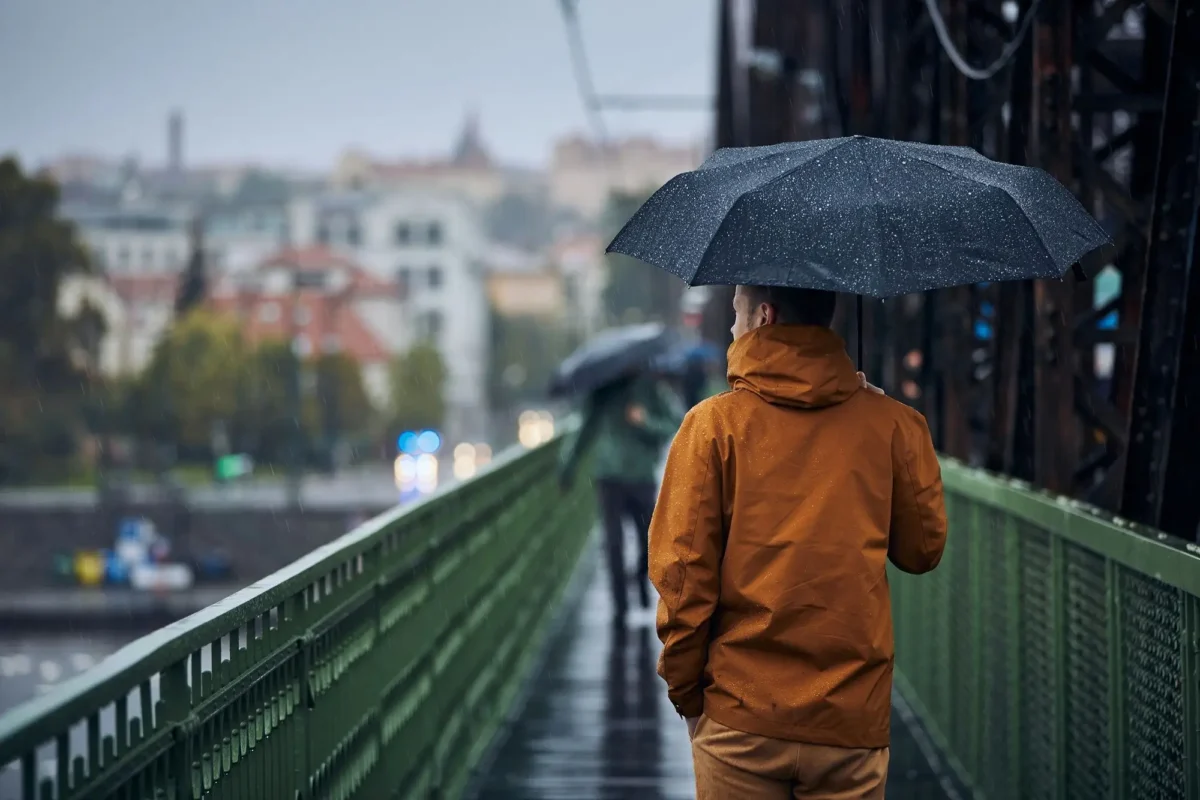 shutterstock_1836480742 1 | TVGURU.cz muž pod deštníkem jde po mostě