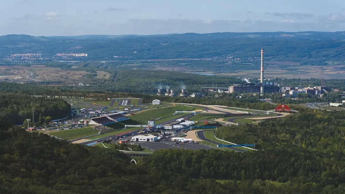 Letecký pohled na severočeské město a autodrom obklopený zelenými lesy