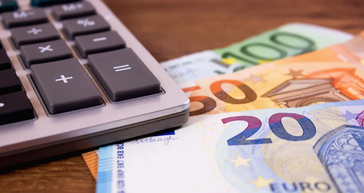 shutterstock_1547387828-2 | TVGURU.cz Na penězích leží kalkulačka.