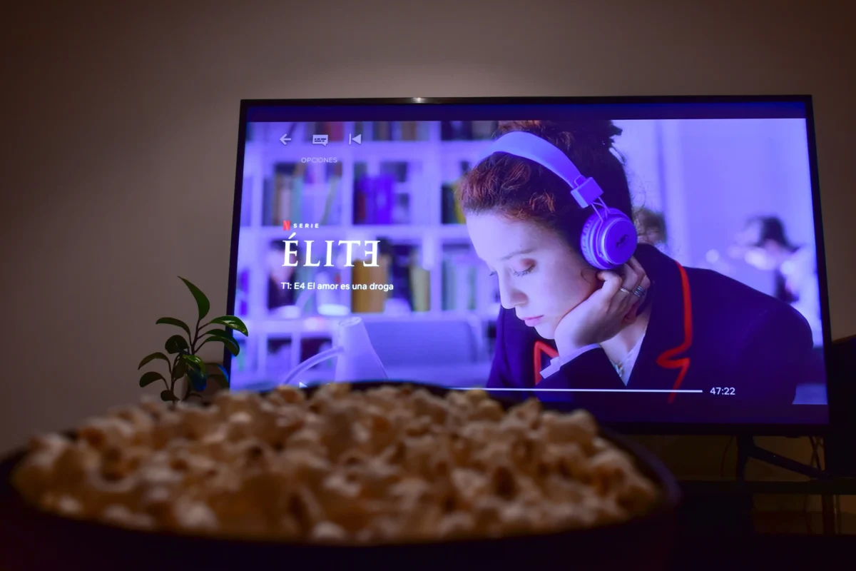 Před televizí, na které je puštěná Elita, stojí mísa s popcornem.