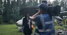 Žena před zpravodajskou kamerou v dešti