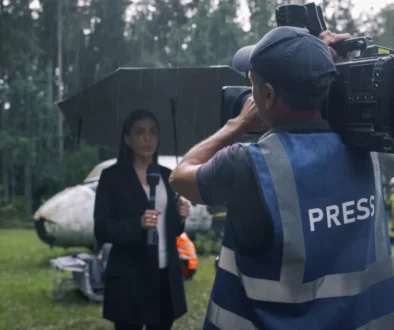 Žena před zpravodajskou kamerou v dešti