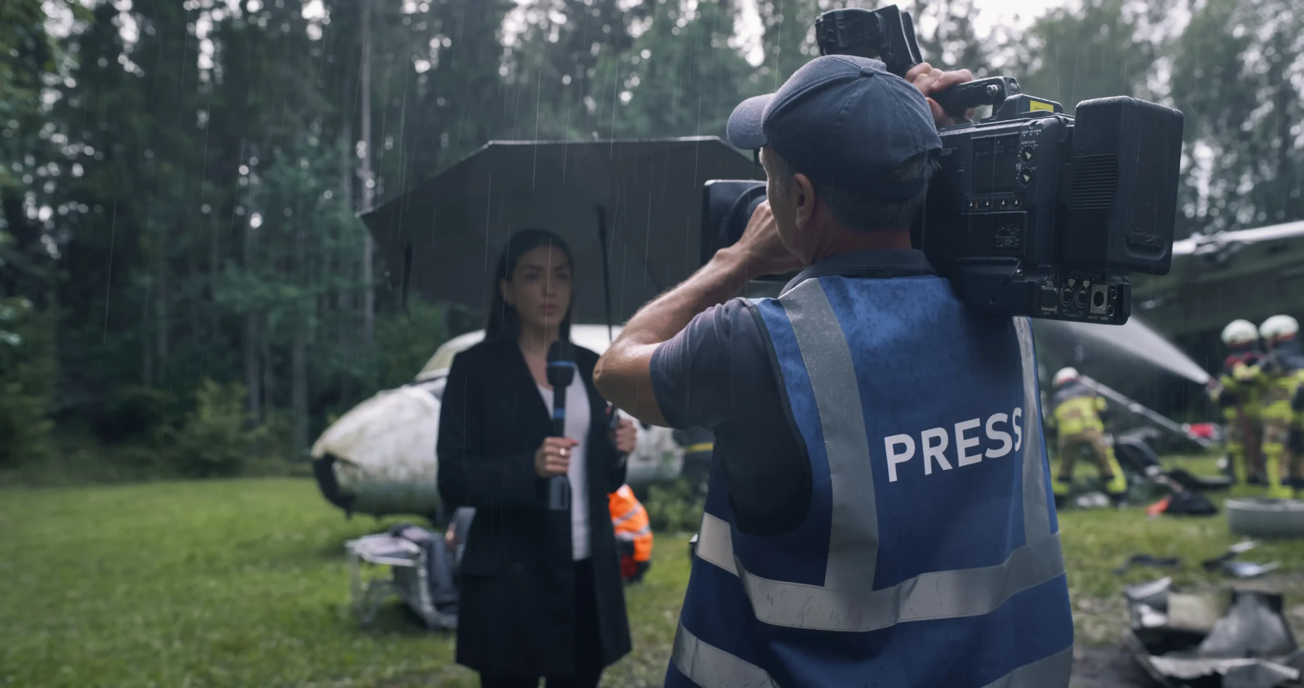 Žena před zpravodajskou kamerou v dešti