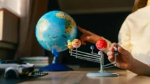 Dětské ruce a model planet sluneční soustavy