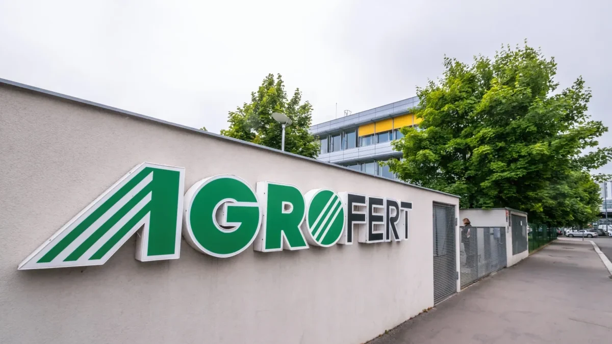 Exterior wall with a large AGROFERT sign in green letters and a striped logo, set beside a sidewalk and trees in the background.