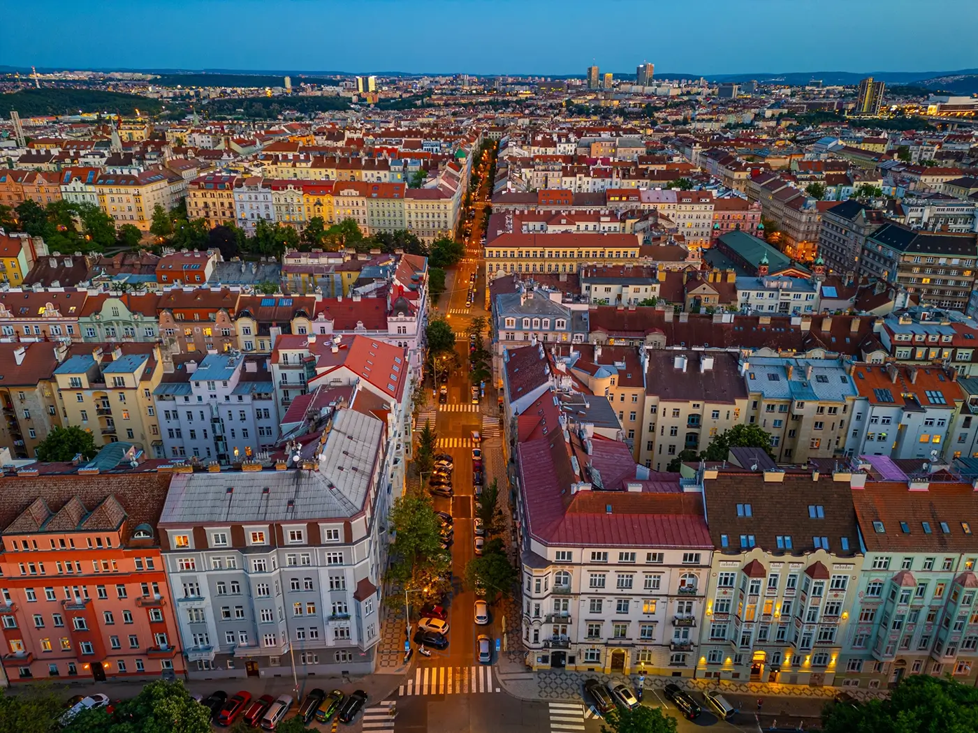 Pražská čtvrť s osvětlenými ulicemi při rozednění