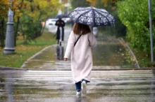 Žena jde po silnici s deštníkem.