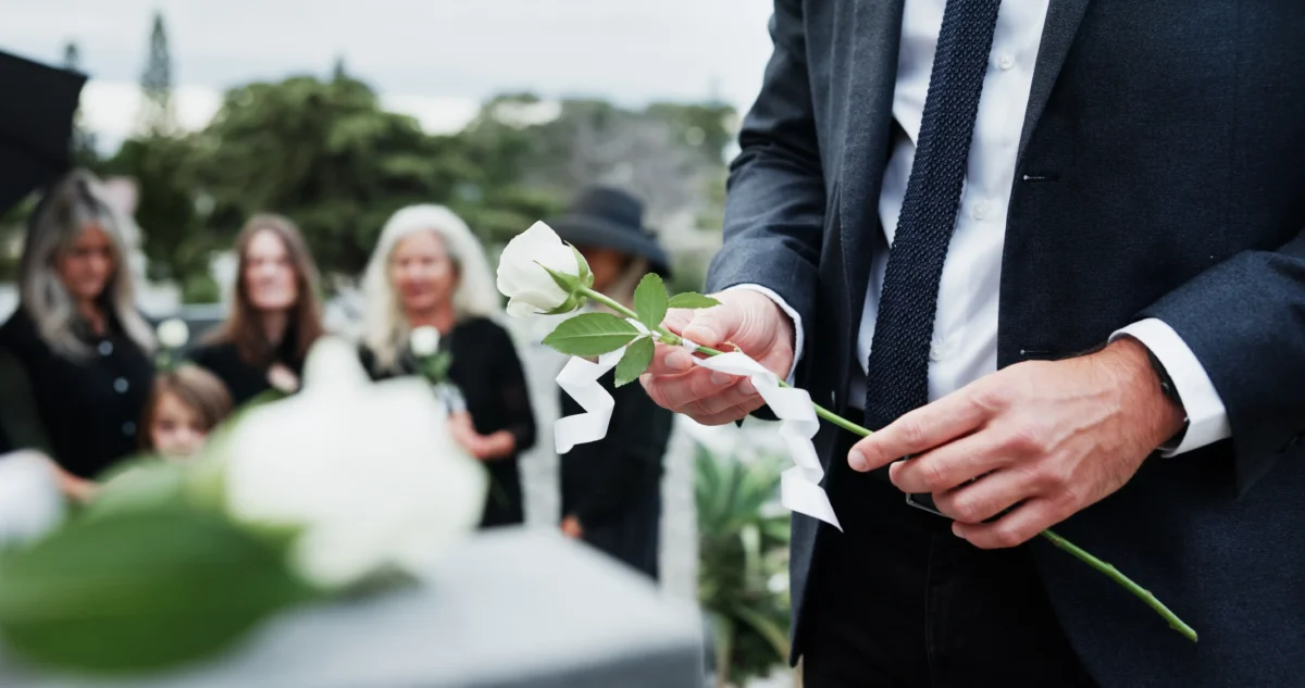 shutterstock_2756797837-2 | TVGURU.cz Muž nad rakví drží bílou růži.