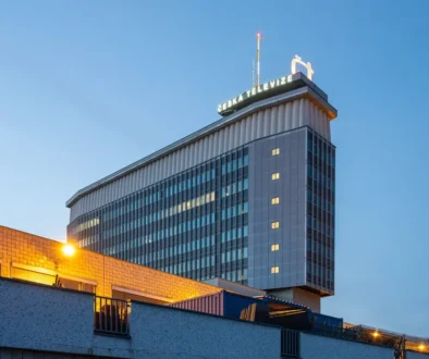 Budova celostátní veřejnoprávní televize s osvětlenou střechou při rozednění