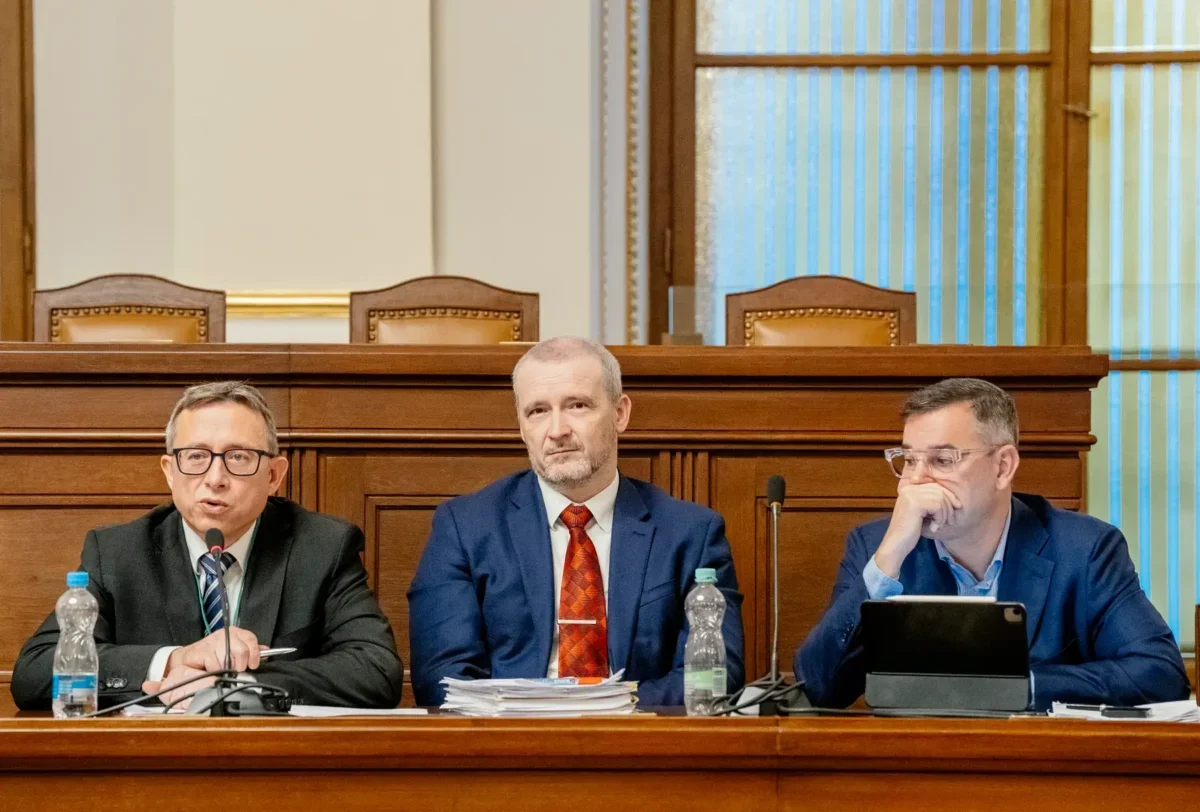 Mojmír Hampl sedí vedle dvou mužů.