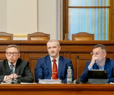 Mojmír Hampl sedí vedle dvou mužů.
