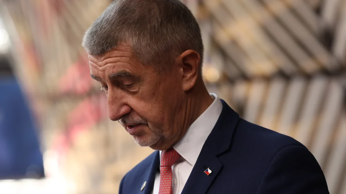 Starší muž v modrém obleku s červenou kravatou klopí hlavu a vypadá rozladěně
