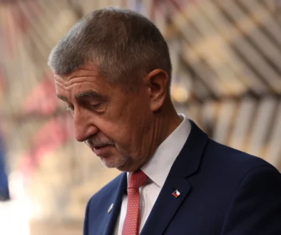 Starší muž v modrém obleku s červenou kravatou klopí hlavu a vypadá rozladěně