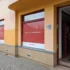 Budova domu s oranžovou fasádou, v přízemí jsou velké výkladní skříně, v nich nápis VZP