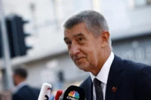 Andrej Babiš stojí u mikrofonu.