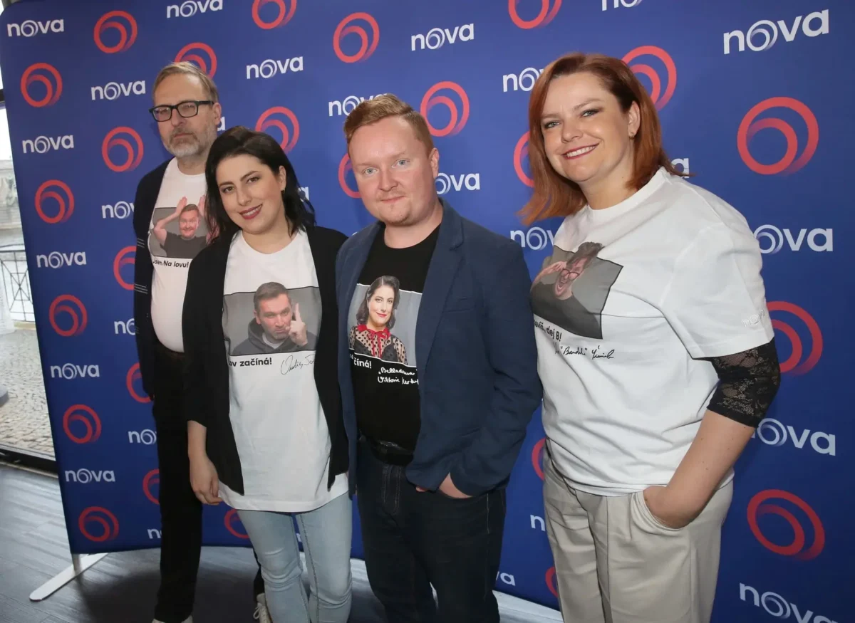profimedia-0943089552 1 | TVGURU.cz Group of four adults posing for a photo in front of a blue Nova backdrop with red circular logos; two women wear white printed T-shirts, one man in a blazer, and another man with glasses.