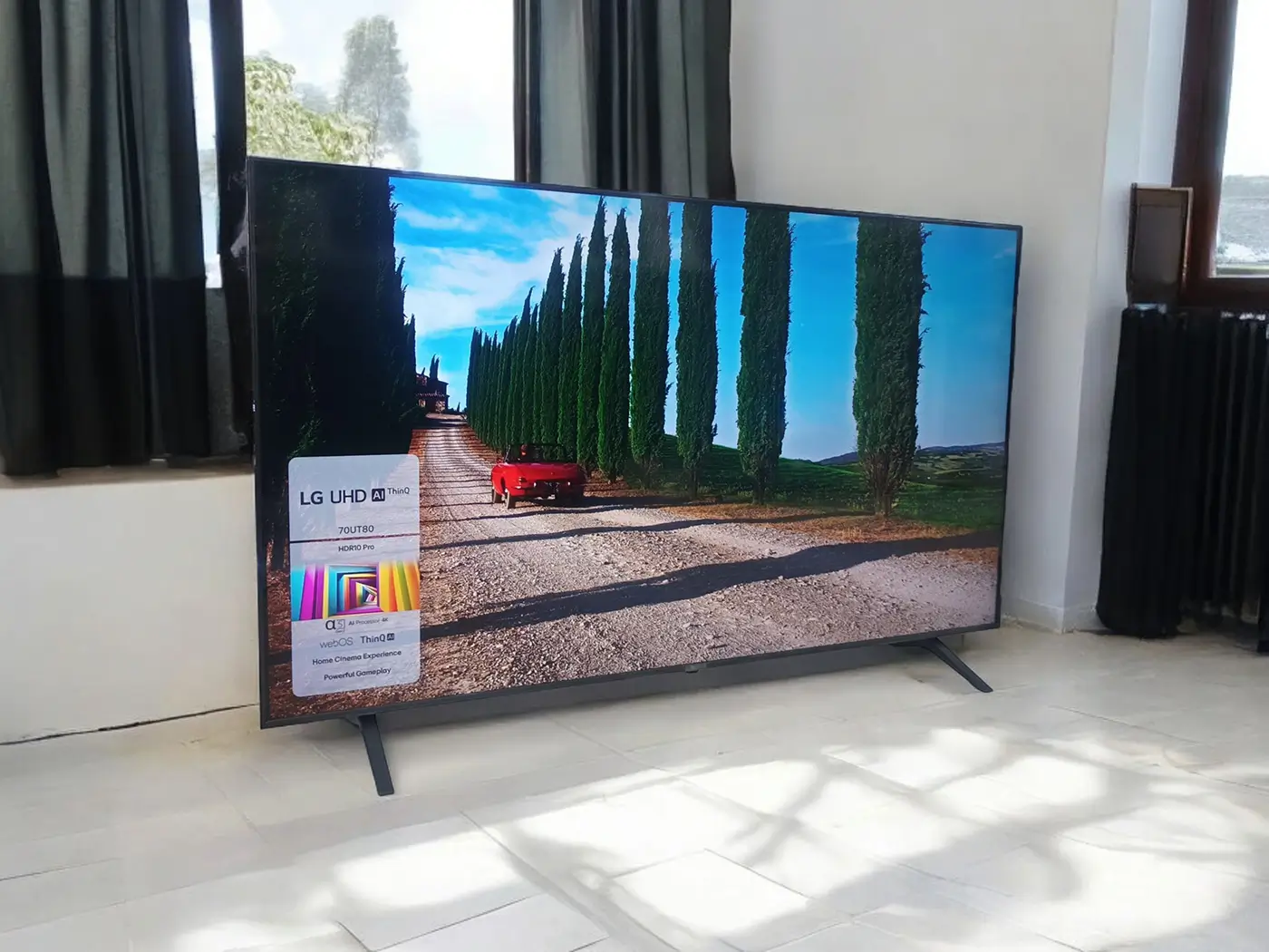 Obývací pokoj s velkou 4K televizí, za kterou se nachází okno