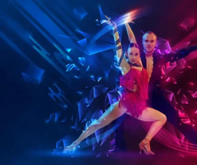Duo of ballroom dancers mid-leap on a neon-lit stage, woman in a pink fringe dress and man in dark attire, with blue and magenta geometric light effects.