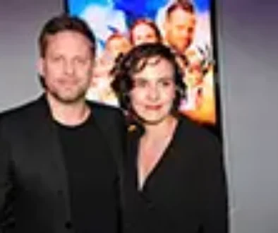 Mladý muž a mladá žena stojí před filmovým plakátem v černém oblečení