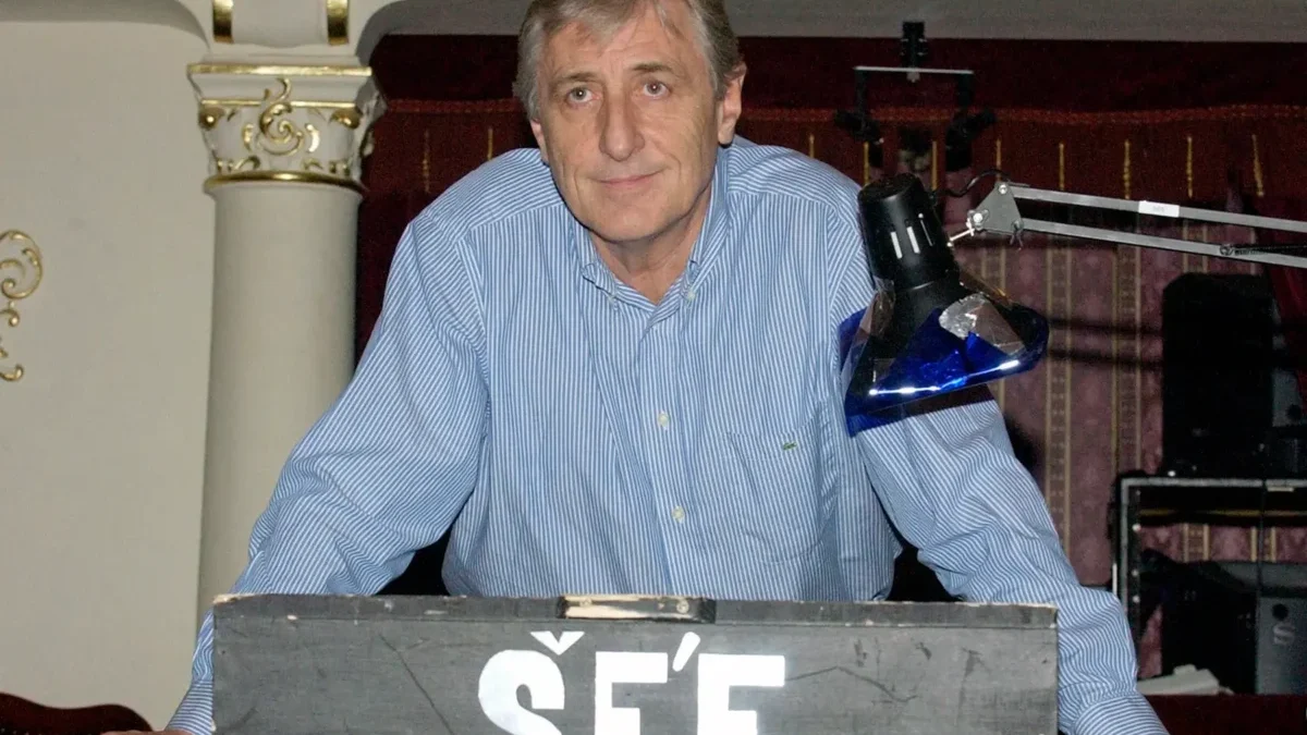 Karel Heřmánek se opírá o pult.