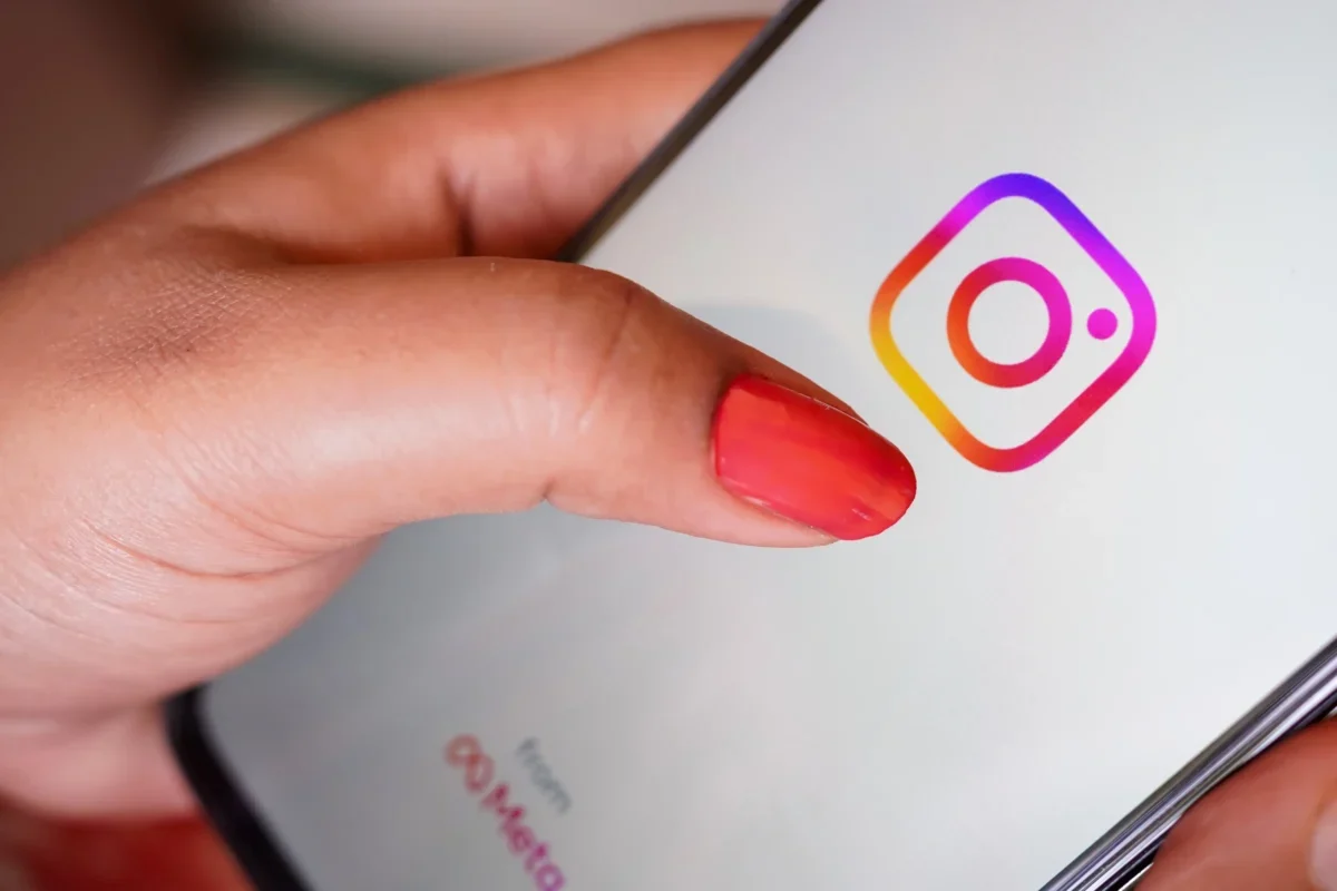 Žena prstem míří na ikonku Instagramu.