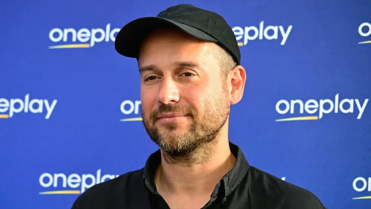 Muž stojí před nápisy Oneplay.
